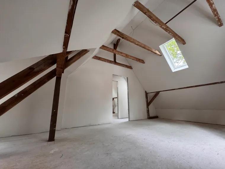 Privater Dachausbau in Berlin-Karow mit sichtbaren Holzbalken und Dachfenster
